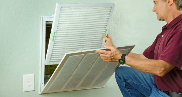 Professional repair service man or diy home owner a clean new air filter on a house air conditioner which is an important part of preventive maintenance.